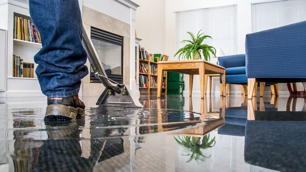 Technician extracting standing water from a flooded living room floor